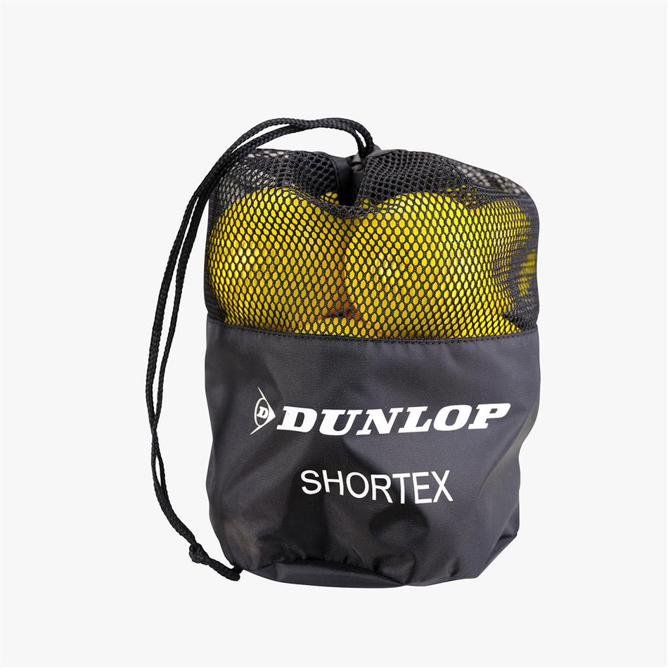 A black mesh drawstring bag with Dunlop logo and SHORTEX text partially reveals yellow Dunlop Shortex Foam Tennis Balls (12 Pack)—beginner-friendly kids’ tennis balls by Dunlop.