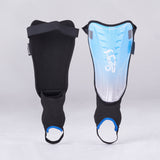 Two blue Kookaburra Octane Shinguards with foot straps stand upright against a plain gray background, displaying both front and back. These Kookaburra shinguards offer multi-purpose protection with added ankle disc safety features.