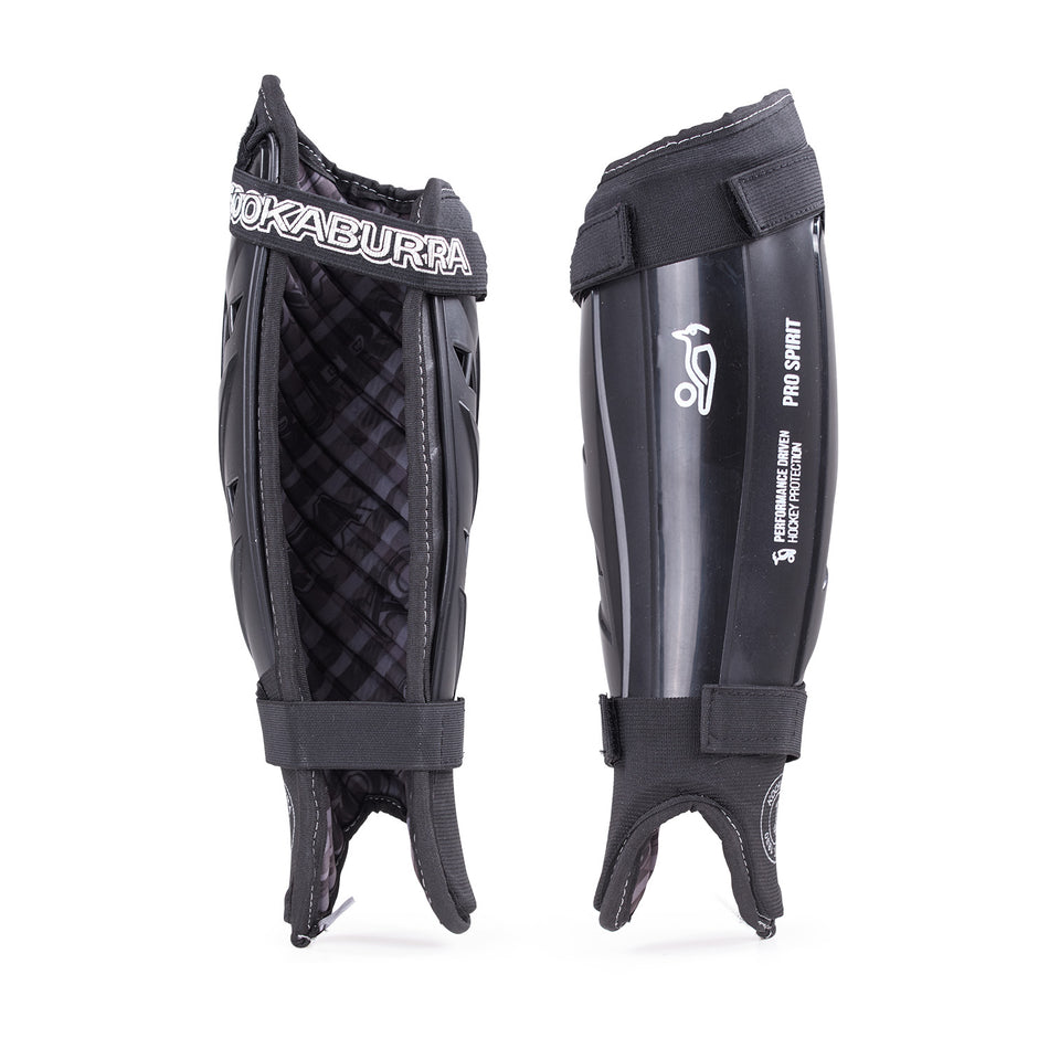 Pair of black Kookaburra Pro Spirit Shinguards: one side shows padded foam backing, the other reveals a hard shell with white logo. Both include ankle straps, foot loops, and reinforced spine for extra support.