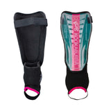 Two Kookaburra Octane Shinguards in Marine/Pink with ankle and foot straps. One shows the front with a transparent cover revealing a pink/green design and branding; the other displays the padded, protective back with ankle disc.