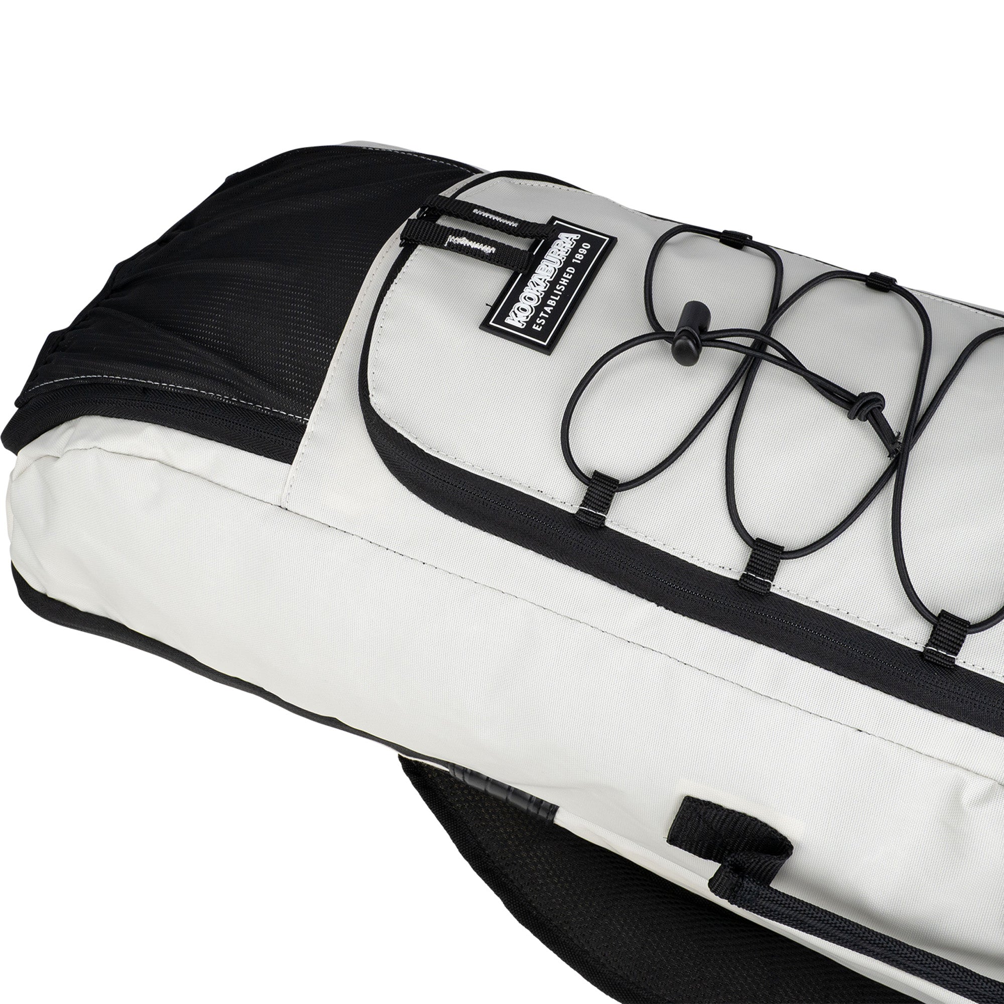 A close-up of the Kookaburra Axis Hockey Kit Bag 2026 by Kookaburra, showing its black and white design with gusseted pockets, a top zip pocket, stitched patch logo, and exterior elastic cord for securing items.
