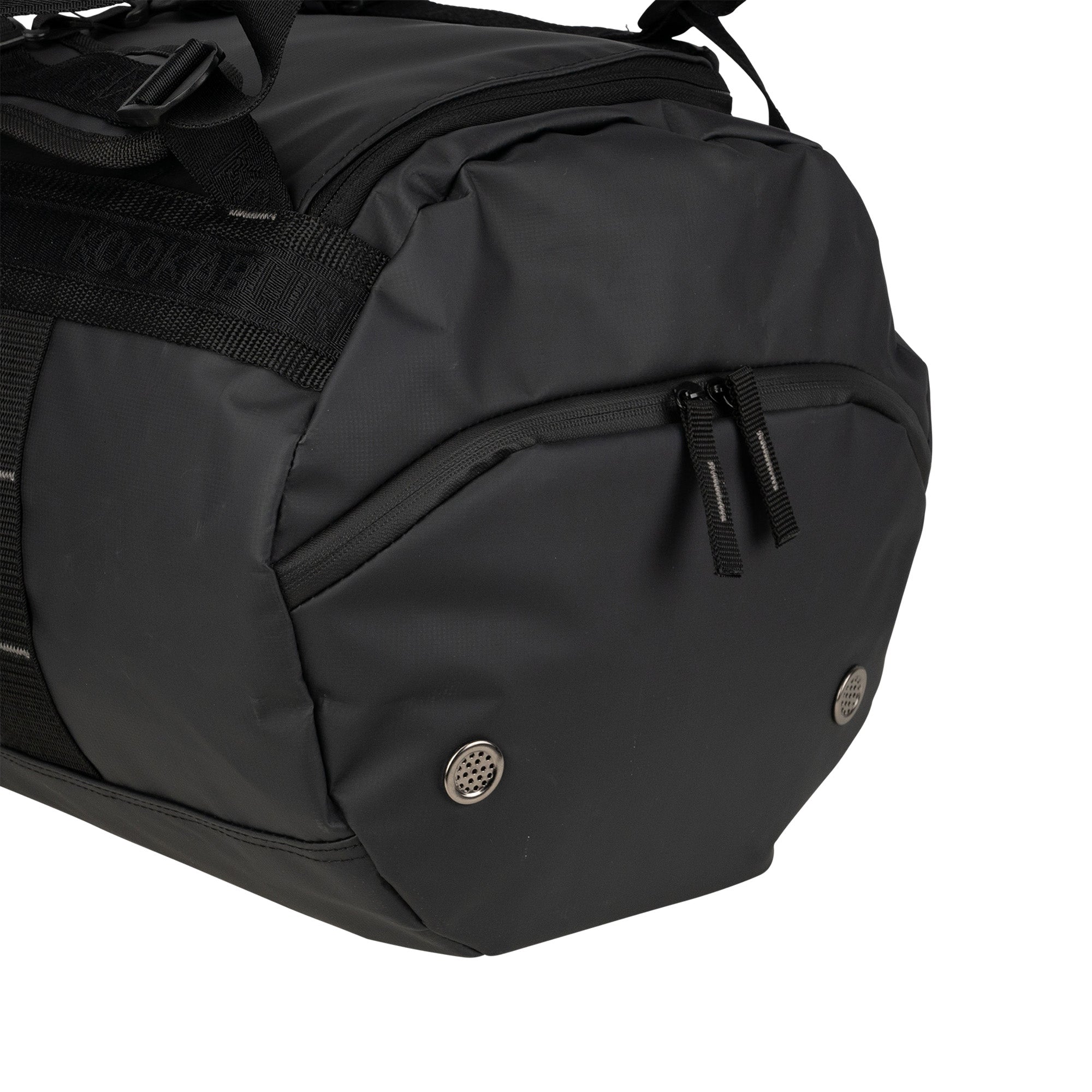 Close-up of the Kookaburra Pro Switch Holdall by Kookaburra—a black multi-purpose bag made from heavy-duty, water-resistant tarpaulin, with a zippered side pocket and two metal grommets at the bottom for ventilation.