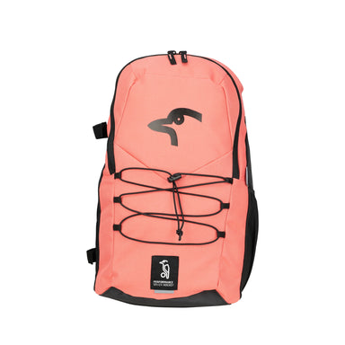 The Kookaburra Edge Rucksack 2026 by Kookaburra features coral pink and black colors, a black stylized bird logo, ergonomic design, black zipper, elastic cord on the front pocket, and a PERFORMANCE label at the bottom.
