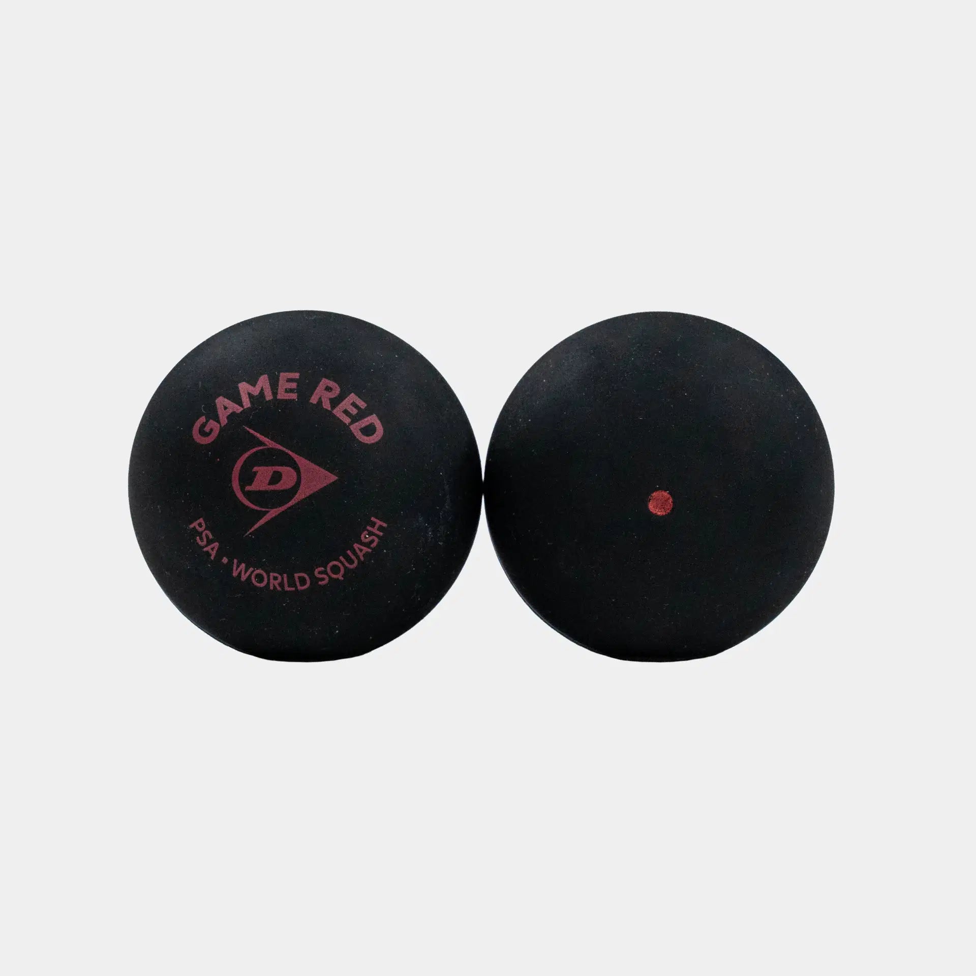 Two black Dunlop squash balls are shown against a white background; one ball is marked with the words “GAME RED,” “DUNLOP,” and “PSA WORLD SQUASH,” identifying it as part of the Dunlop Game Red Squash Ball (4 x 3 Ball Box)—a higher bounce ball designed for players looking to improve—while the other features a single red dot.