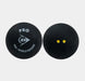 Set against a plain white background, two black Dunlop Pro Squash Balls (12 x 1 Ball Box) are shown. One ball features the “PRO PSA WORLD SQUASH” text and the Dunlop logo, while the other displays two small yellow dots—signifying its low bounce designed for professional-level play. Both balls have a matte texture, highlighting their premium quality from the trusted brand Dunlop.