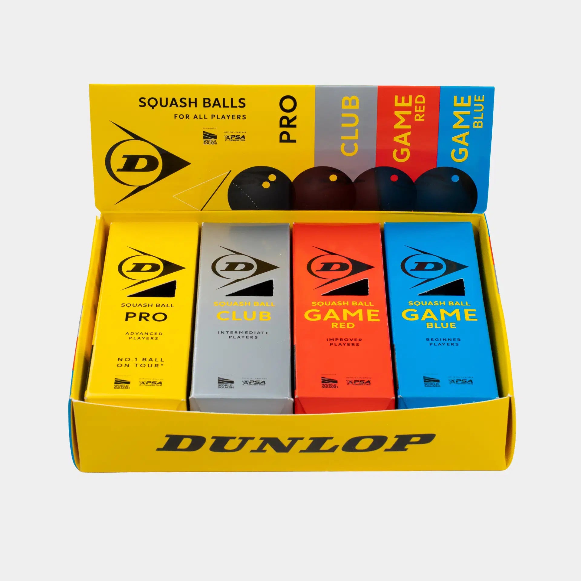 An open yellow Dunlop box showcases the Dunlop Mixed Squash Ball Pack (4 x 3 Ball Box), featuring four types of Dunlop squash balls: Pro (black), Club (silver), Game Red (red), and Game Blue (blue). The front of the box displays the Dunlop brand name in black text.