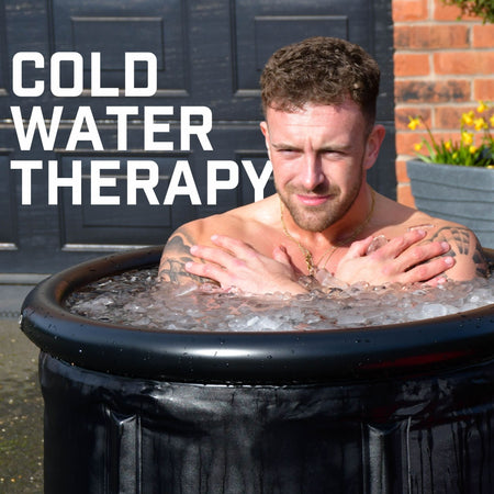 A man sits in the Urban Fitness Recovery Ice Bath by Urban Fitness, arms crossed over his chest. The words “COLD WATER THERAPY” highlight ice bath recovery benefits, with a brick wall and door in the background.