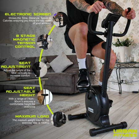 A person uses the Urban Fitness Magnetic Exercise Bike indoors. Key features: electronic screen, 8-stage magnetic resistance, adjustable seat height, max load 100kg. The Urban Fitness logo appears in the corner.