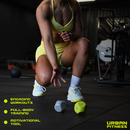 A woman in yellow gym wear kneels, reaching for Urban Fitness Fitness Dice—ideal for home workouts. Text highlights Engaging Workouts, Full-Body Training, and Motivation. The Urban Fitness logo is shown bottom right.