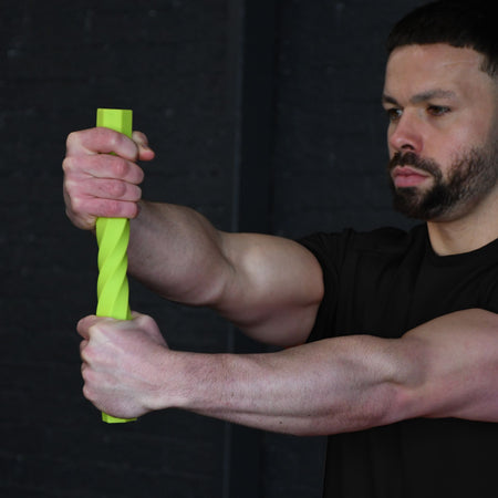 A man in a black shirt holds and twists the Urban Fitness Twist & Flex Resistance Bar with both hands, extending his arms straight out in front of him against a dark background to improve grip strength.