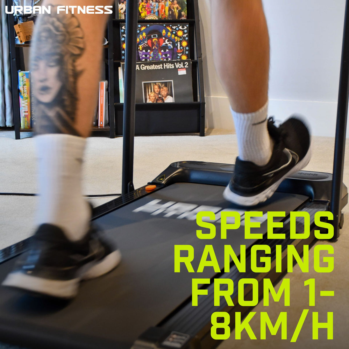 A person with a leg tattoo runs indoors on the Urban Fitness Walking Treadmill by Urban Fitness (speeds: 1–8km/h). Shelves behind display books and a record, highlighting the treadmill’s smart fitness tracking features.