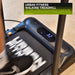A person uses the Urban Fitness Walking Treadmill in black with smart fitness tracking; its digital display reads 3.2. The treadmill features "HERON" on the belt and suits both beginners and advanced walkers.