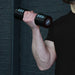 A person in a black shirt lifts the Urban Fitness 2.5kg Adjustable Dumbbell Set by Urban Fitness with their right arm against a dark, textured background.
