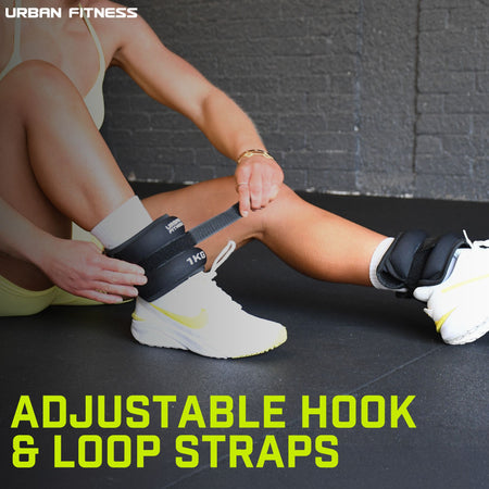 A person secures Urban Fitness Neoprene Ankle/Wrist Weights with adjustable hook & loop straps over white sneakers. "Adjustable Hook & Loop Straps" is shown, with the Urban Fitness logo in the corner.