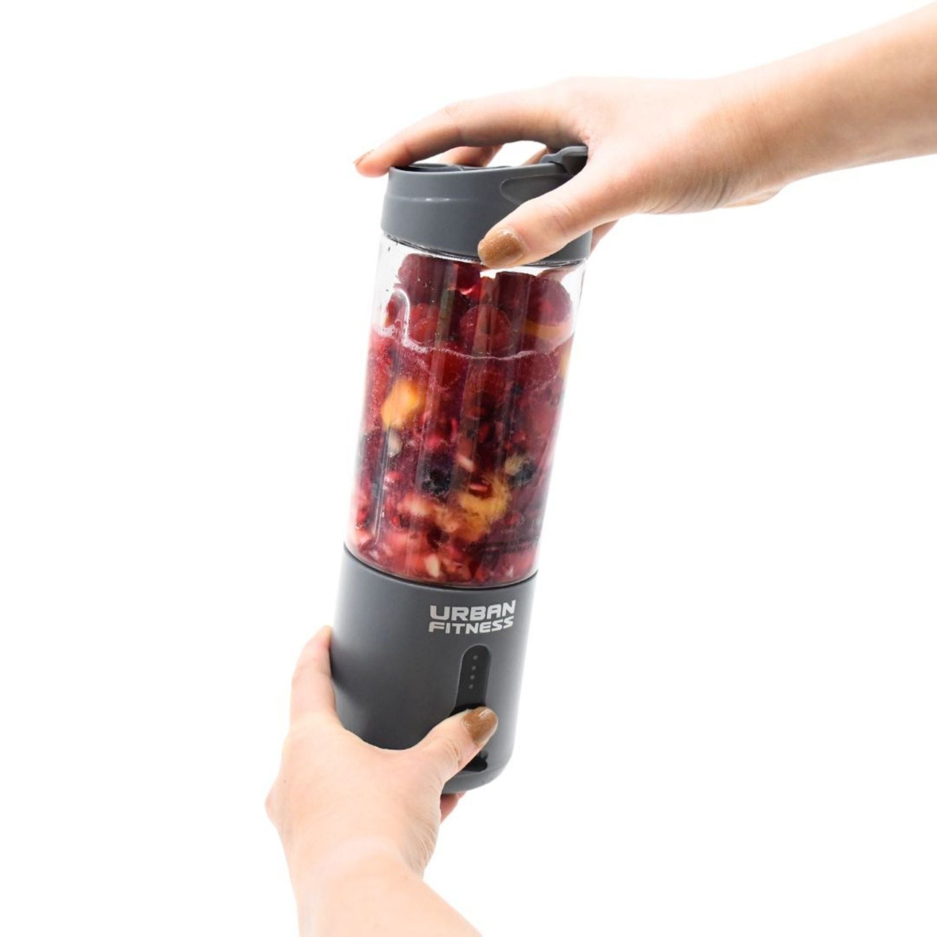 A person operates the Urban Fitness VitalFuse Portable Blender, filled with fruit, using both hands; the rechargeable blender displays the Urban Fitness brand against a plain white background.