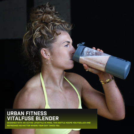 A woman in athletic wear drinks from the Urban Fitness VitalFuse Portable Blender, with the product name and description shown in the lower left corner, emphasizing on-the-go nutrition.
