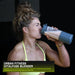 A woman in athletic wear drinks from the Urban Fitness VitalFuse Portable Blender, with the product name and description shown in the lower left corner, emphasizing on-the-go nutrition.