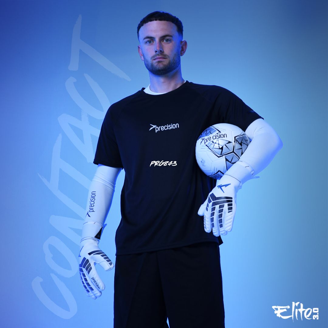 A male goalkeeper faces forward in a black t-shirt and Precision Elite 3.0 Contact Goalkeeper Gloves from Martin Berrill Sports, holding a soccer ball at his hip. The blue-tinted background displays "CONTACT" with Precision and Elite logos.