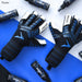 A pair of Precision Training Elite 3.0 Quartz Goalkeeper Gloves in black and blue are shown on a blue and white surface, surrounded by Stealth sports spray bottles to enhance grip.