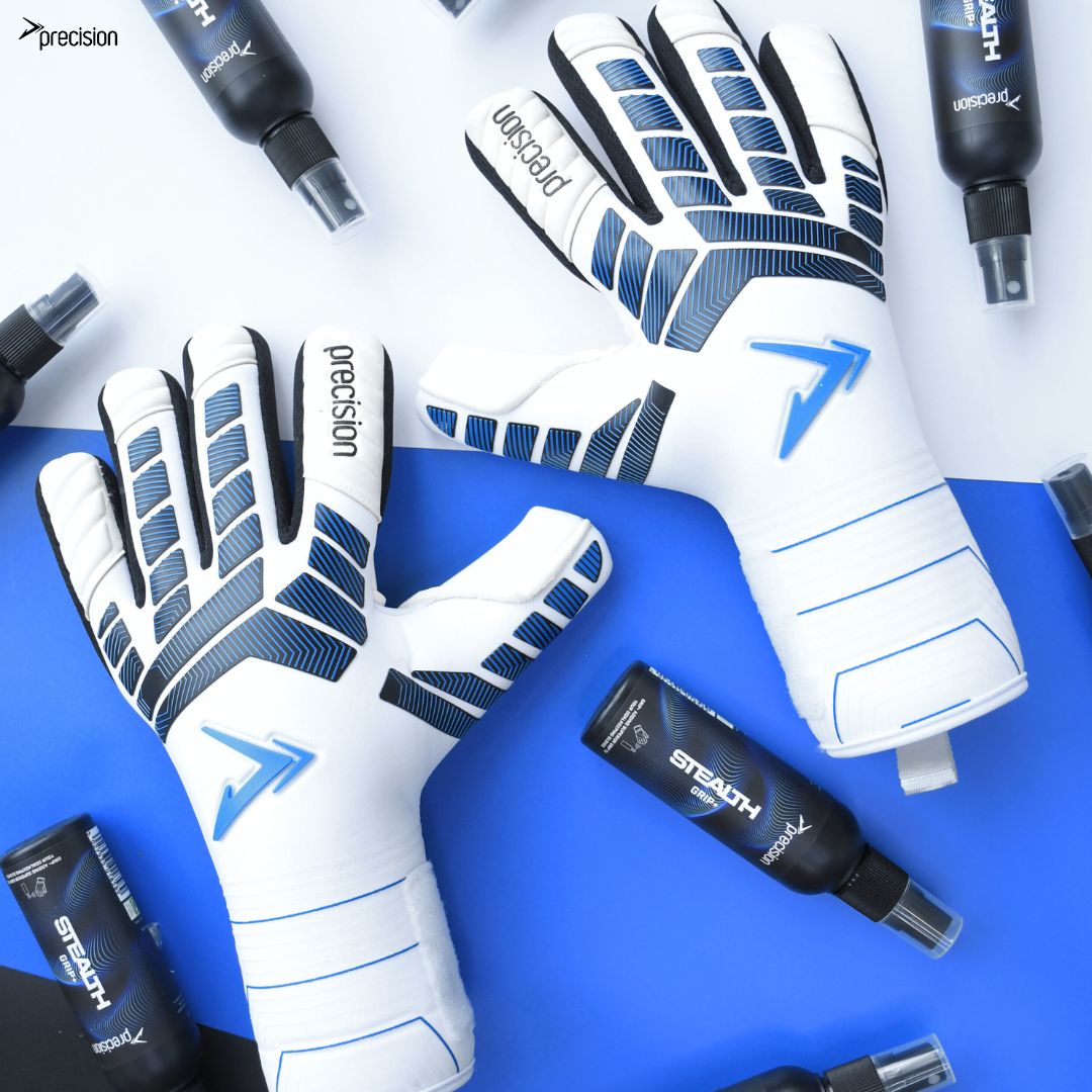 A pair of Precision Training Precision Elite 3.0 Giga Goalkeeper Gloves with elite grip rest on a blue and white surface, surrounded by several black STEALTH-labeled bottles.