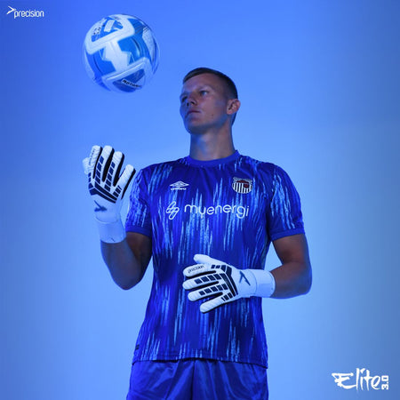 A male football goalkeeper in a blue and purple kit tosses a soccer ball, showcasing his Precision Training Elite 3.0 Giga Goalkeeper Gloves with elite grip. Logos are visible on his shirt and gloves, set against a blue background.