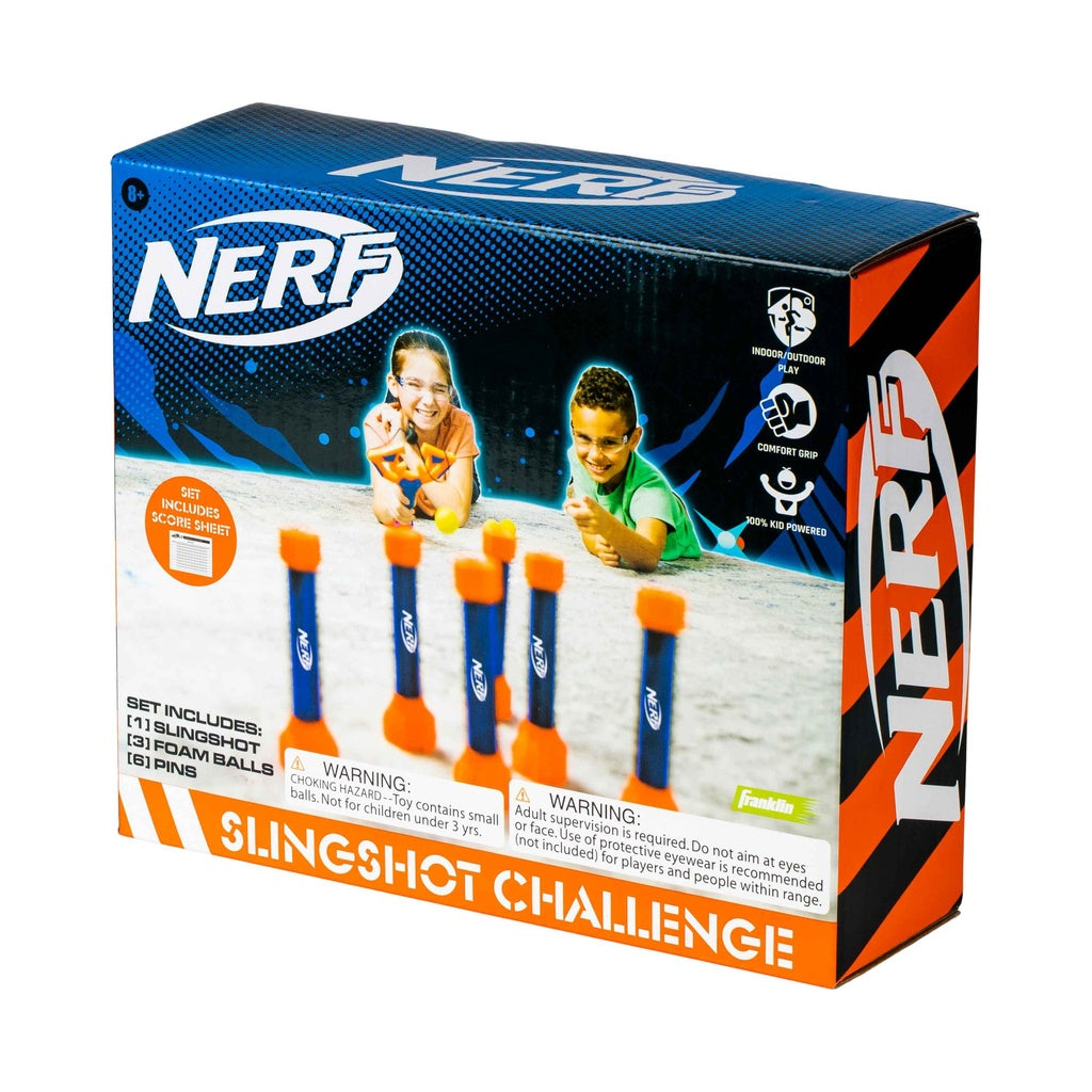 The Nerf Slingshot Challenge by Nerf features two kids playing with a slingshot, three foam balls, and four standing pins—great for indoor or outdoor fun. The box is accented in blue and orange.