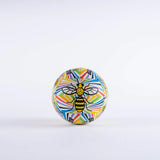 The Gilbert Ambassador Signature Netball by Gilbert features a geometric design and a bold black and yellow bee at the center. This size 5 ball stands out against a plain white background.