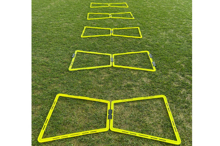 Six Samba Sports Samba Pro Agility Trapeze Set hurdles are lined up on green grass, fading into the distance—essential agility training equipment for speed and coordination drills.
