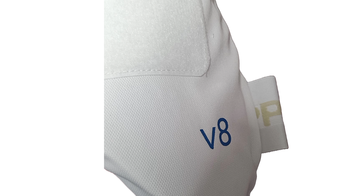 Close-up of Aero P1 Strippers V8 by Aero, featuring white textured fabric with "v8" in blue, EVA foam for hip protection, and a stitched tab with partial gold lettering on a plain white background.