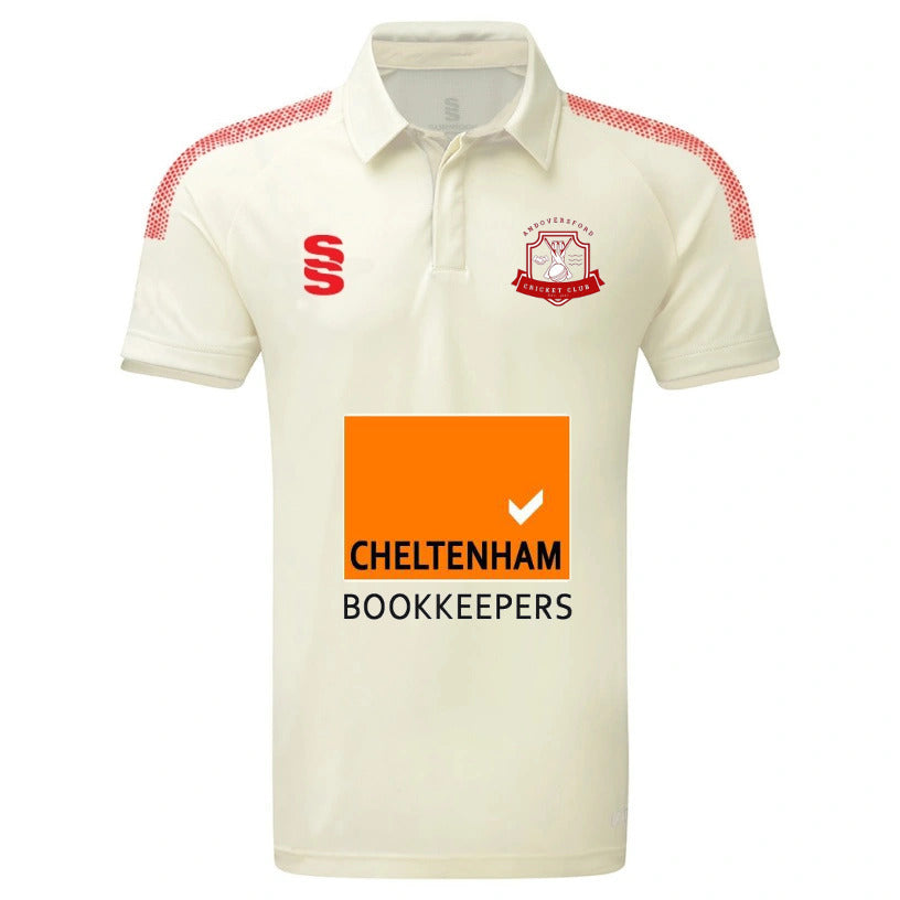 The Andoversford CC Dual S/S Match Shirt by Surridge is a cream slim-fit cricket shirt with red shoulder accents, VAPADRI tech for comfort, a team logo, red “S” branding, and a bold orange "Cheltenham Bookkeepers" sponsor on the front.