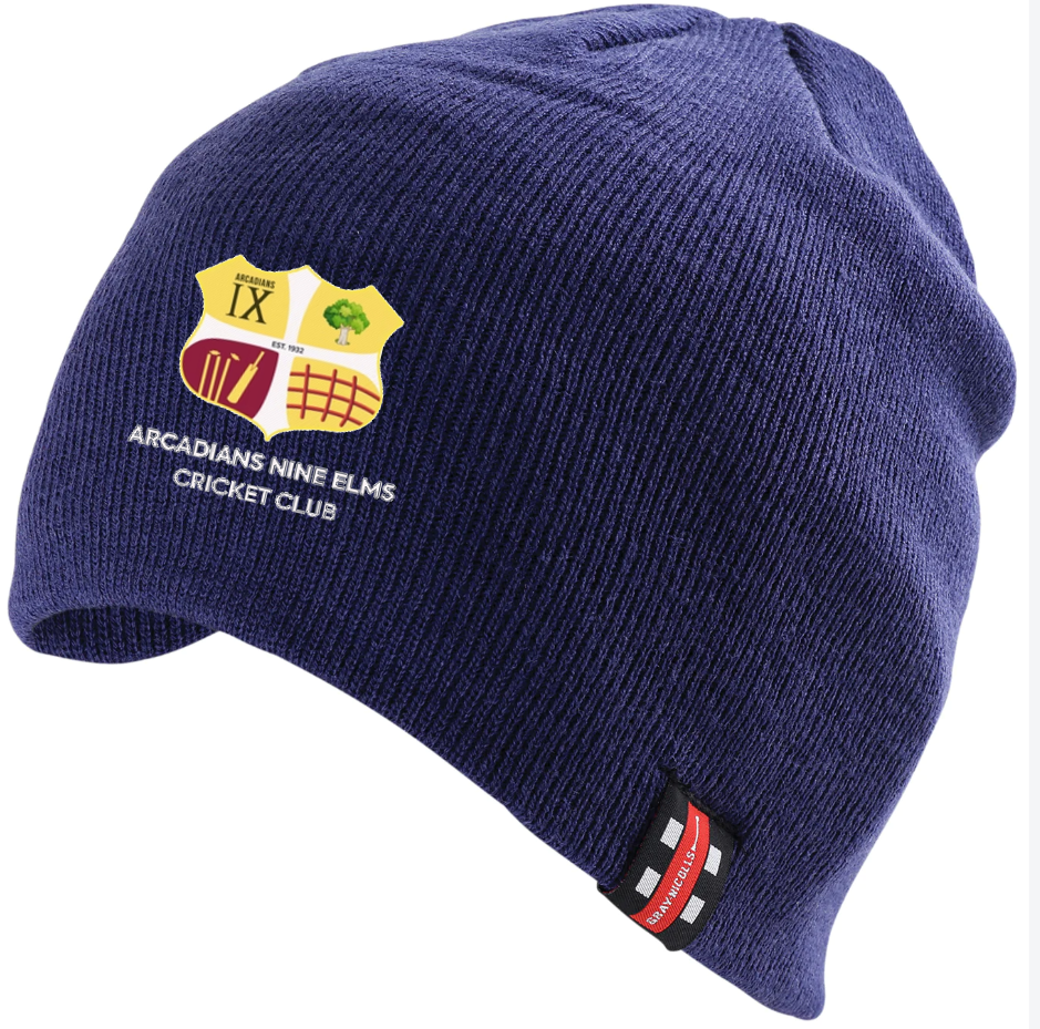 The Arcadians Nine Elms CC Beanie Hat by Gray Nicolls is navy with the club logo and name embroidered on the front and a small black, red, and white tag on the cuff.