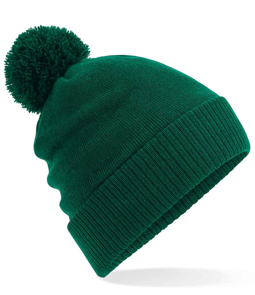 The Kingswood Village CC Thermal Beanie by Martin Berrill Sports features a green color, large pom-pom, folded brim, and soft fleece lining, shown on a white background.