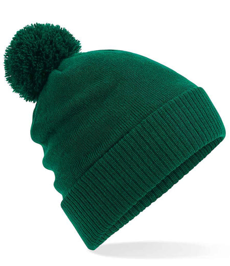 The Kingswood Village CC Thermal Beanie by Martin Berrill Sports features a green color, large pom-pom, folded brim, and soft fleece lining, shown on a white background.