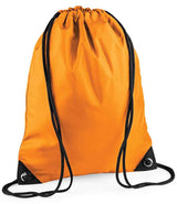 The PenCarrie BagBase Premium Gymsac is a bright orange, water-resistant drawstring bag with black strings and reinforced black corners with metal grommets, shown standing upright on a white background.