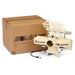 The Bola BOLA Junior Bowling Machine is pictured beside its shipping box. Designed for junior cricket practice, the cream-colored machine from Bola features dual throwing wheels and a ball feeder attachment on top, with a visible power cable.