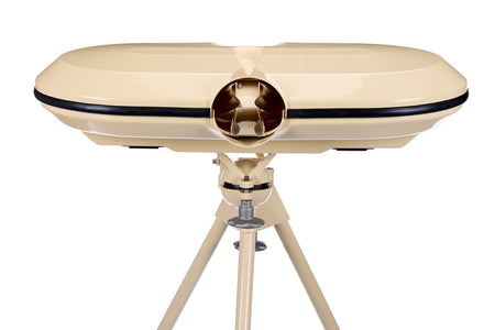 A beige Bola dual-lens device, set on a coordinating tripod against a white background, resembles vintage binoculars or a viewfinder and is designed for use with the Bola Professional Bowling Machine during cricket batting practice.