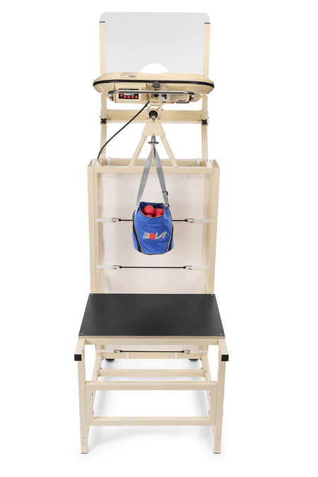 A beige medical testing station featuring a black bench, adjustable platform, hanging blue bag with red balls, and white backboard is positioned next to the Bola Bowling Machine Stand on Wheels by Bola, seamlessly blending function and versatility in the space.
