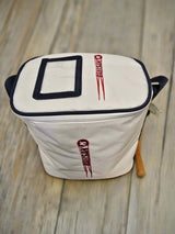 A white, rectangular Katchet BallSak by Katchet with black trim and two red MasterChef logos—one on top and one on the side—rests on a wooden surface. A wooden handle peeks out from the side. Ideal for stylishly storing hockey balls.