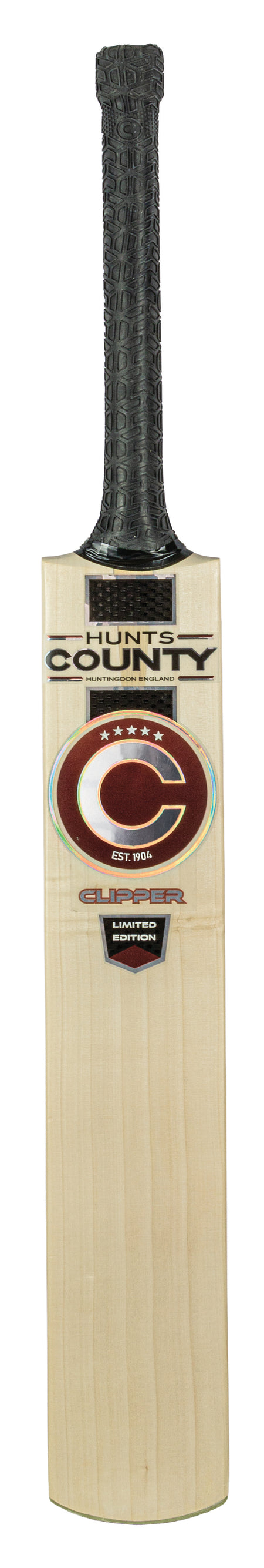A wooden cricket bat with a black textured grip and Hunts County branding on the blade, featuring a large red and white C logo with additional text and labels below. Crafted from English Willow, the Hunts County Clipper Limited Edition Junior Cricket Bat (2026) is ideal for those seeking quality in junior cricket bats.
