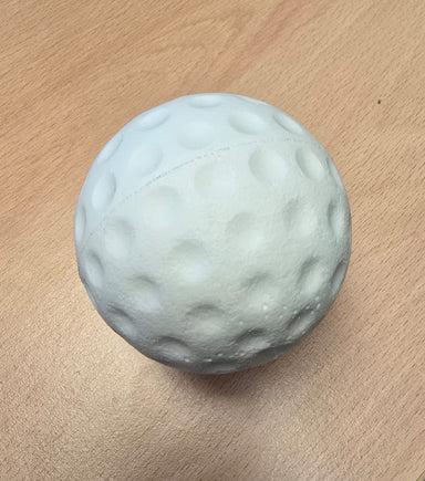 A white, dimpled, ball-shaped object resembling a golf ball sits on a light wooden surface, similar to Bola Senior Bowling Machine Practice Balls (White) by Bola.