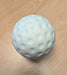 A white, dimpled, ball-shaped object resembling a golf ball sits on a light wooden surface, similar to Bola Senior Bowling Machine Practice Balls (White) by Bola.
