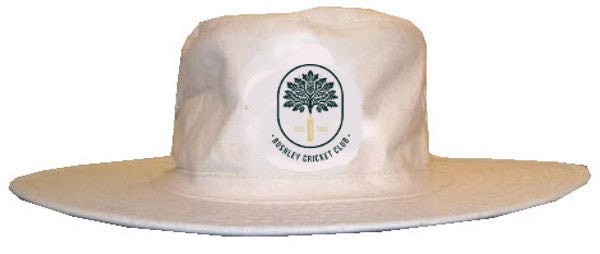 The Hunts County Bushley CC Cricket Sunhat is a wide-brimmed white hat featuring the Bushley CC club badge, which displays a central tree and "Burnley Cricket Club" text below.