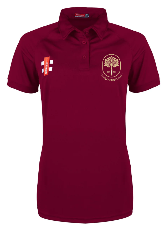 The Gray Nicolls Bushley CC Matrix V2 Ladies Polo Shirt is maroon, short-sleeved with buttons, features the cricket club logo on the left chest, an England flag and red sponsor tag above it, and is made of moisture-wicking fabric for training.