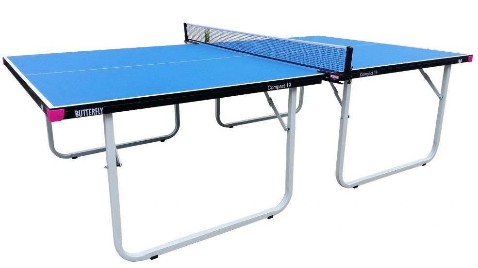 A blue Butterfly Compact 19 Wheelaway Table Tennis table, featuring a black frame and white legs, is set up with a net attached in the center. The Butterfly brand name is visible on the side, highlighting this as an indoor table tennis table. The table stands out with its clean look against a plain white background.