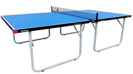 A blue Butterfly Compact 19 Wheelaway Table Tennis table, featuring a black frame and white legs, is set up with a net attached in the center. The Butterfly brand name is visible on the side, highlighting this as an indoor table tennis table. The table stands out with its clean look against a plain white background.