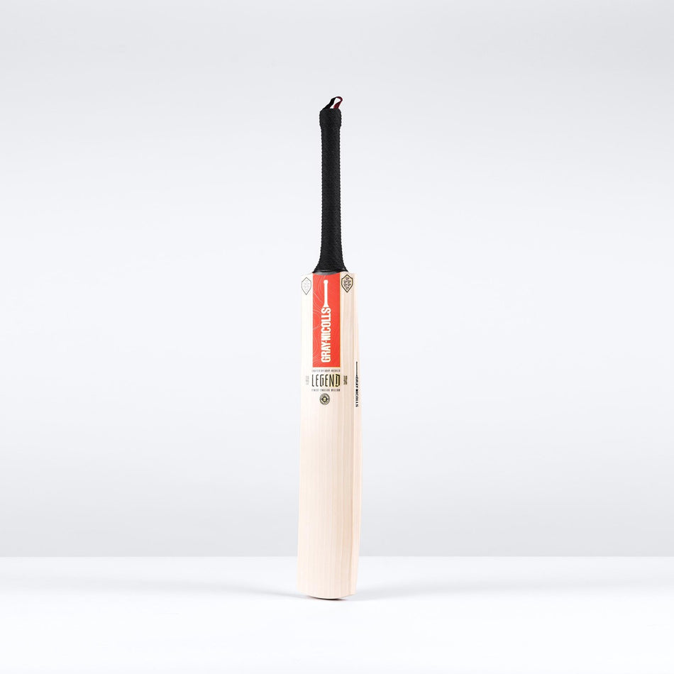 The Gray Nicolls Legend Gold Edition SH Cricket Bat, crafted from English willow with a black handle and red GRAY-NICOLLS label, stands upright against a plain white background.