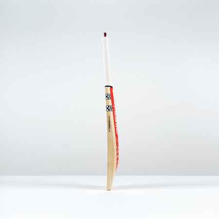 The Gray Nicolls Neocore Pro SH Cricket Bat 2026, showcasing a white handle and checkered design with advanced NEOCORE technology, stands upright on a white surface against a plain, light gray background.