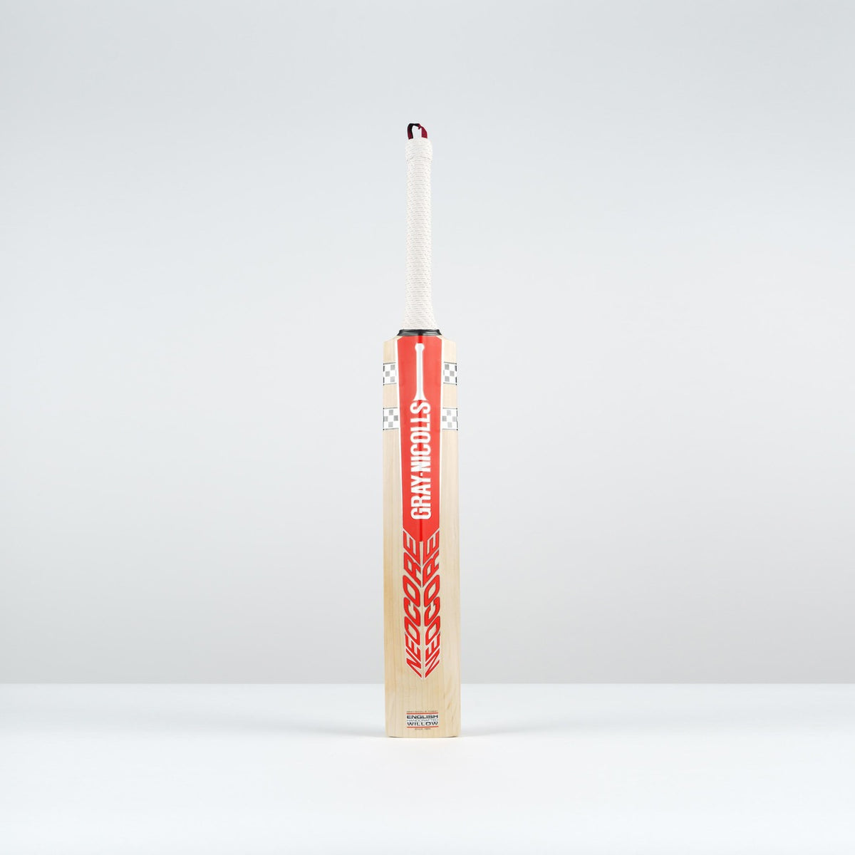 The Gray Nicolls Neocore Pro SH Cricket Bat 2026 stands upright on a plain light gray surface, featuring a Pro Shape with a red and white design, set against a light gray background.