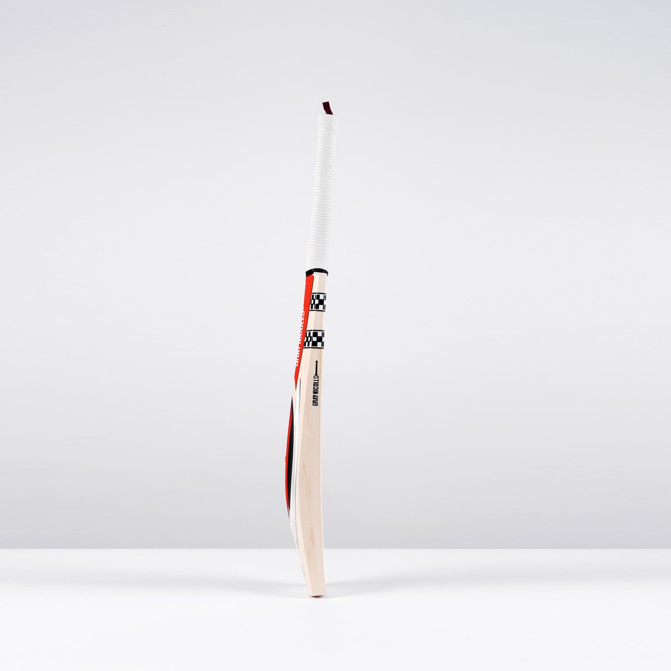 The Gray Nicolls Powerscoop 500 SH Cricket Bat stands upright on a white surface against a light gray background, featuring a wrapped handle and a polished wooden blade with red, black, and white accents.