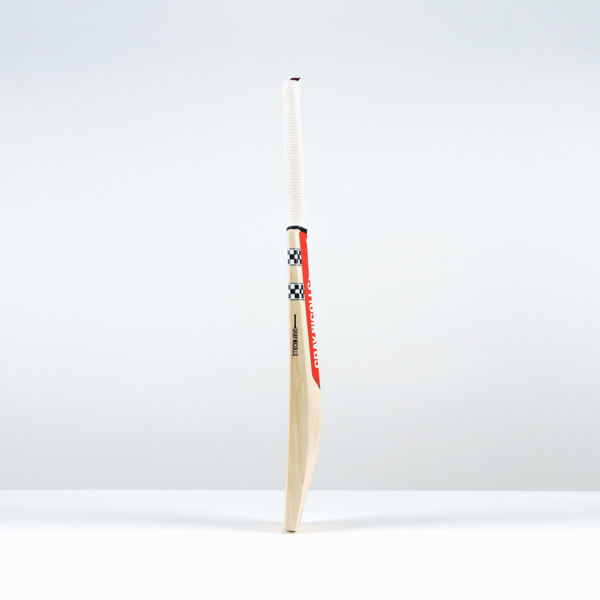 The Gray Nicolls Classic Pro Performance SH Cricket Bat 2026 features a large edge profile, white handle, red and black accents, and a checkered design, standing upright on a white surface against a light background.